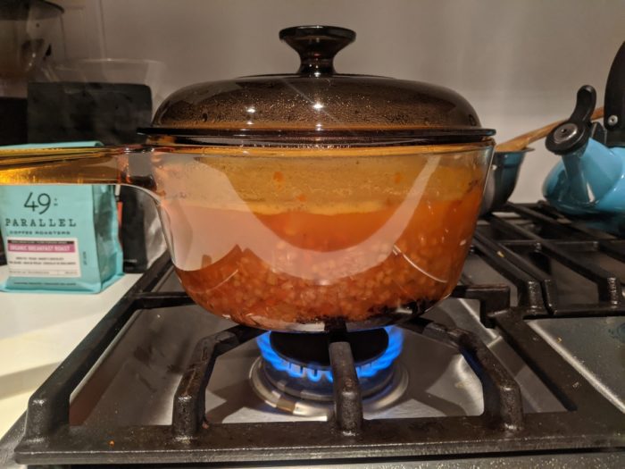 Red lentil soup cooking in a glass pot